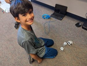 Student is smiling as they learn how to code and interact with Cozmo robot.